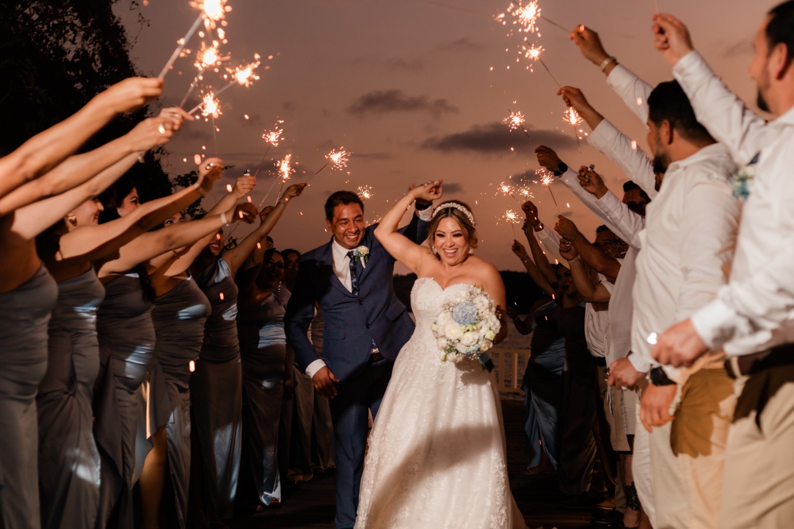 Liz y Ricardo celebrando con luces de bengala en su boda
